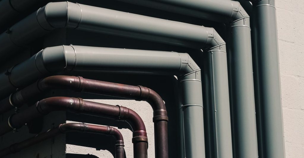 Close-up of industrial pipes forming a pattern on a building's exterior wall, shot outdoors.