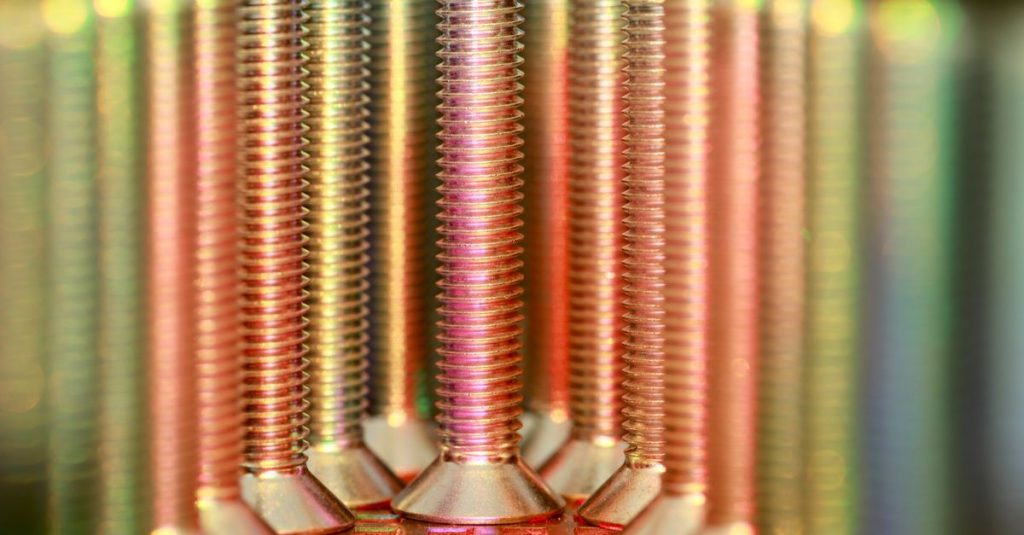 Vibrant close-up of metallic screws in rainbow hues, showcasing industry essentials.