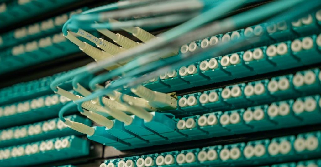 Detailed view of fiber optic cables connected to a server rack, showcasing modern technology.