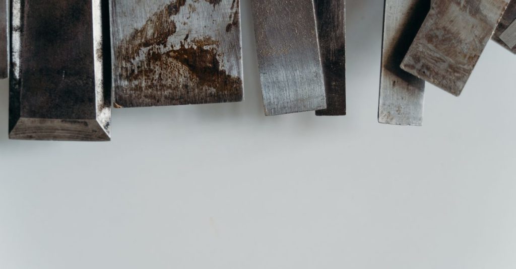 Sincik Hurdacı An abstract still life of textured metal pieces on a white surface.