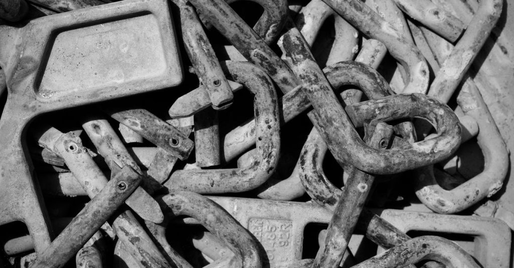 A detailed black and white photo of a pile of weathered metal clamps, conveying an industrial theme.