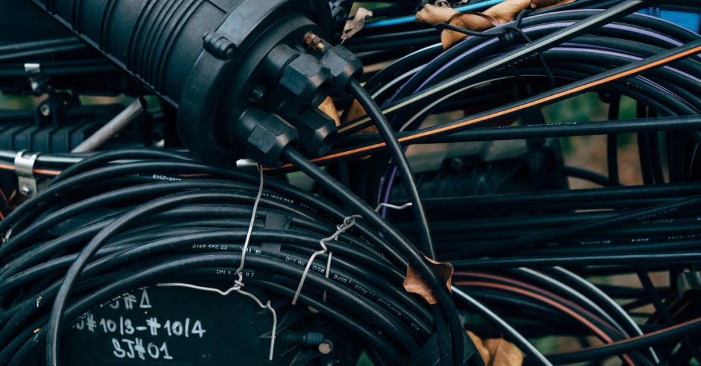 Close-up view of intertwined black cables and connectors in an outdoor telecom setup.