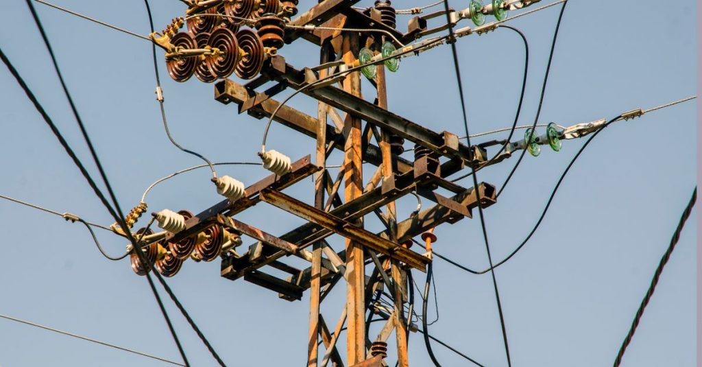Close-up of a rustic utility pole and transmission lines against a clear sky.