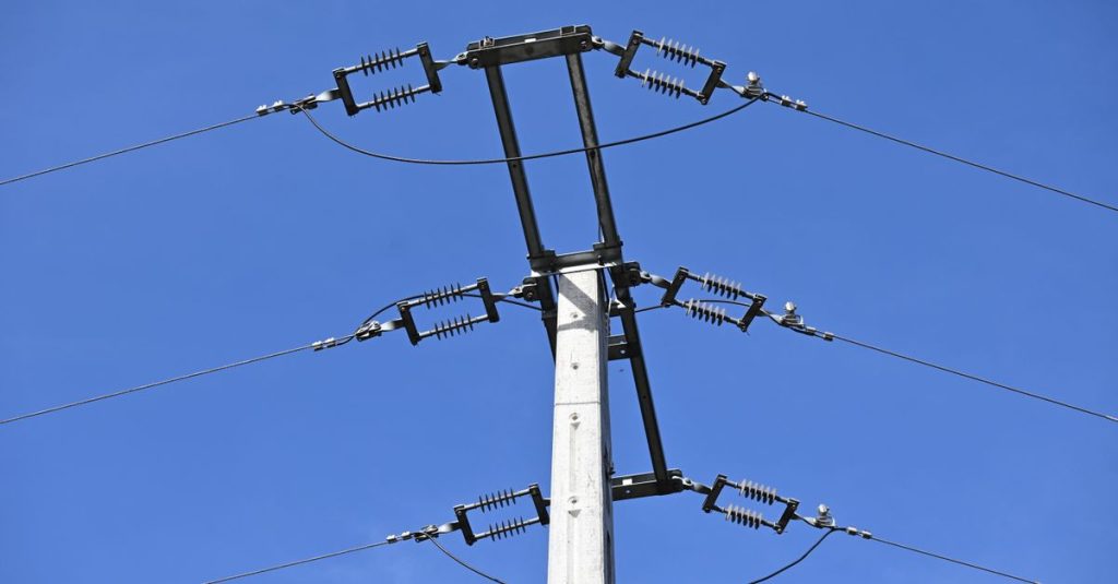 A close-up view of an electricity pole with wires against a clear blue sky, showcasing infrastructure.