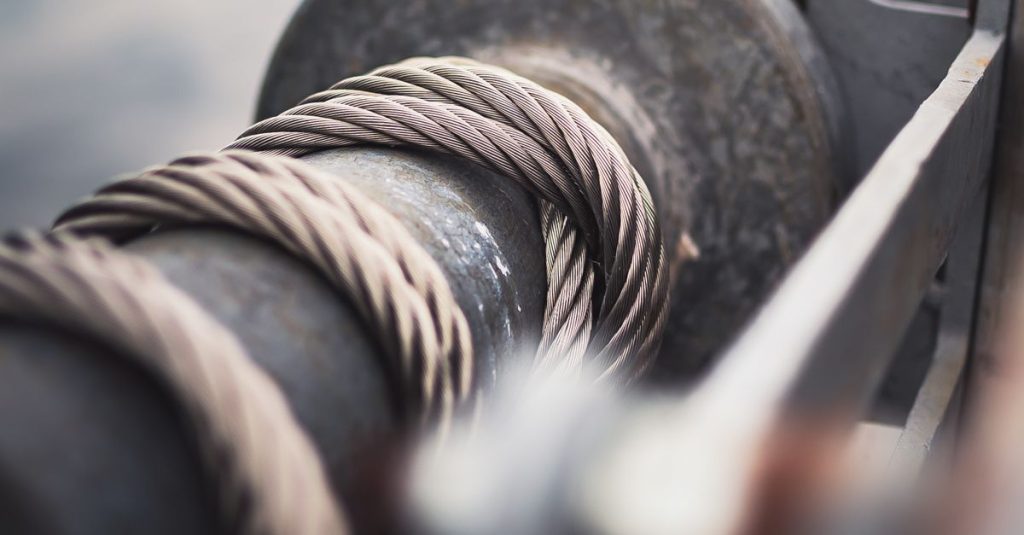 Detailed view of a strong steel cable wrapped around a mechanical reel, showcasing industrial strength.