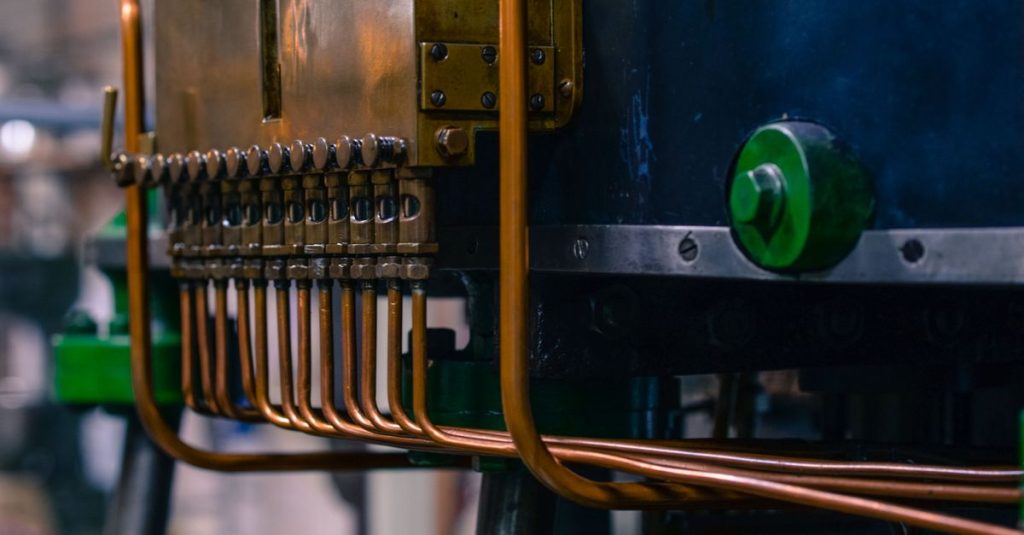 Detailed view of industrial machinery featuring copper tubing and steel components in a factory setting.