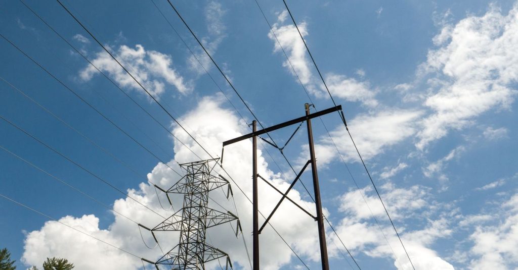 High-voltage power lines and towers set against a vibrant blue sky with scattered clouds.