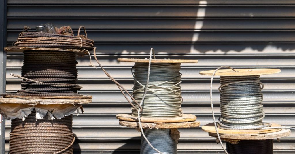 Multiple large spools of industrial cable placed outdoors in front of a closed shutter.