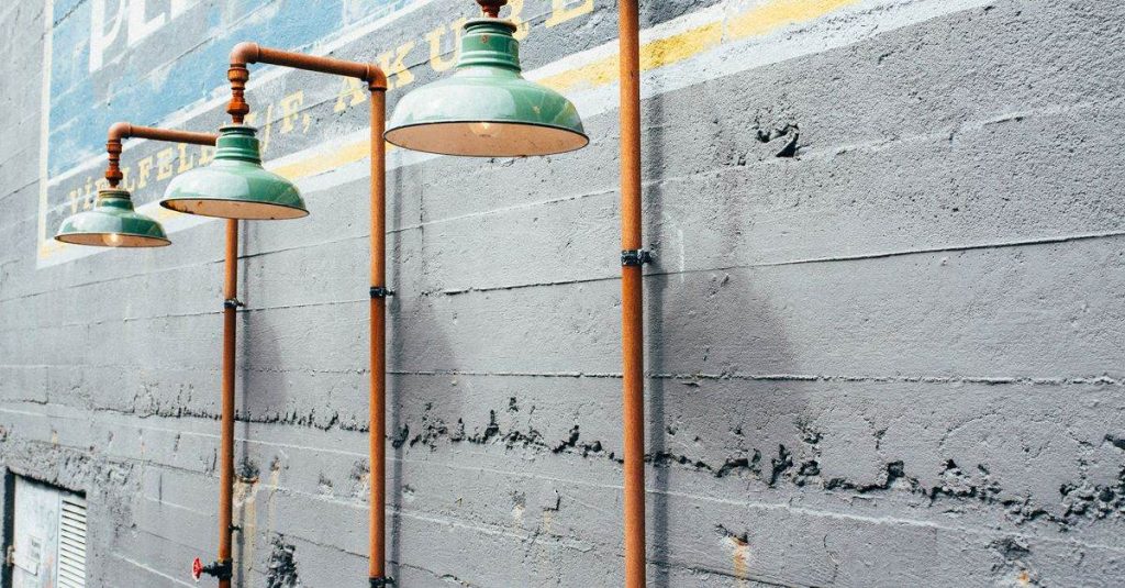 Outdoor vintage lamps with copper piping against a textured concrete wall, urban design