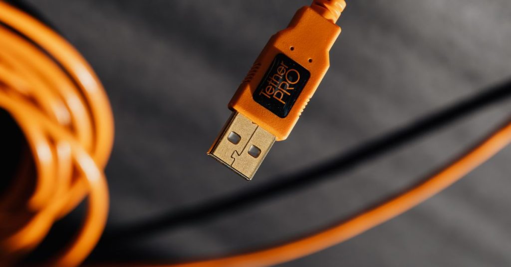 Macro shot of an orange TetherPro USB cable with high detail and shallow focus.