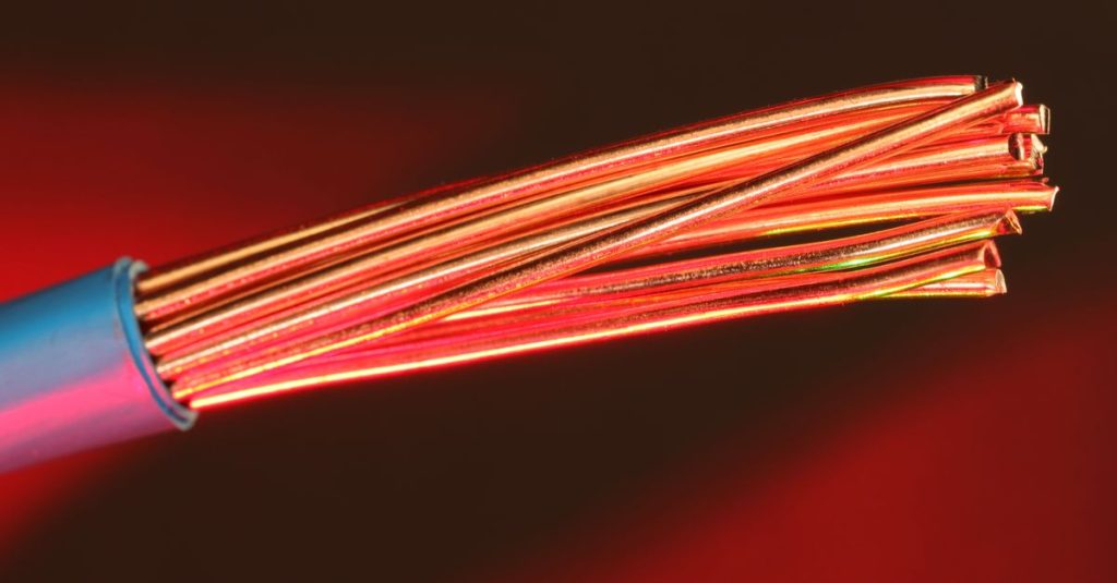 Detailed image of copper wires illuminated by red light, highlighting texture and color.