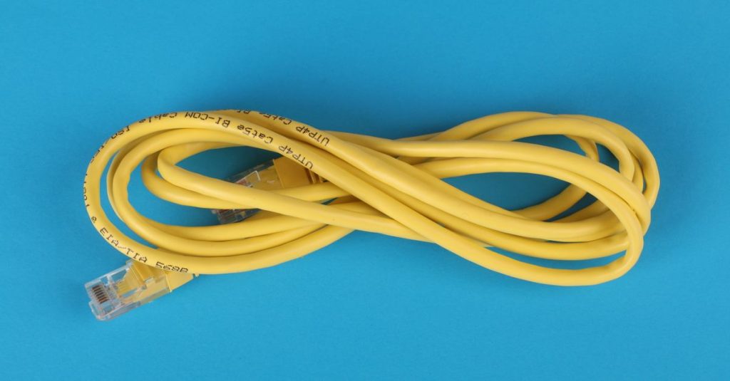 High-angle view of a yellow ethernet cable on a bright blue background.