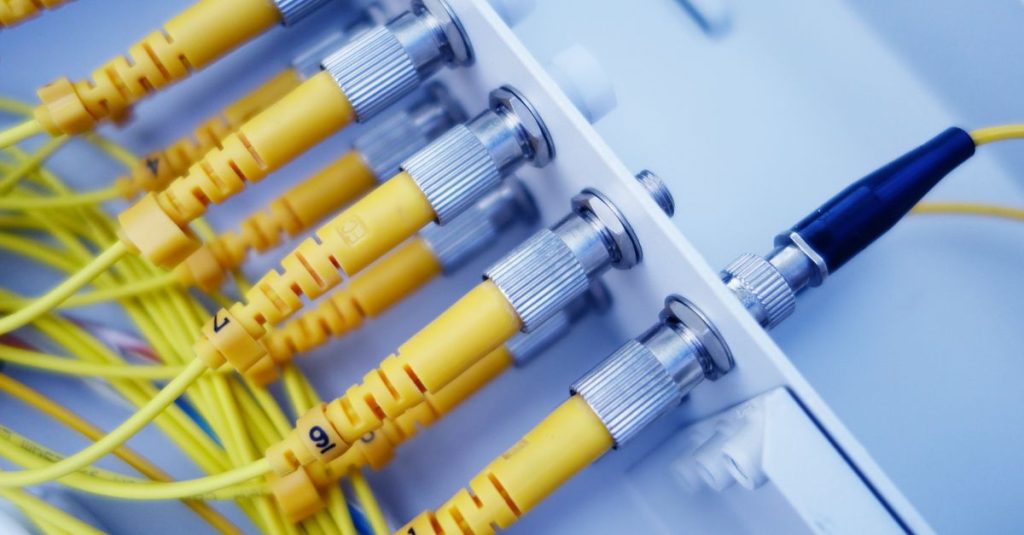 Close-up of yellow fiber optic cables in a network server, showcasing fast data transfer.