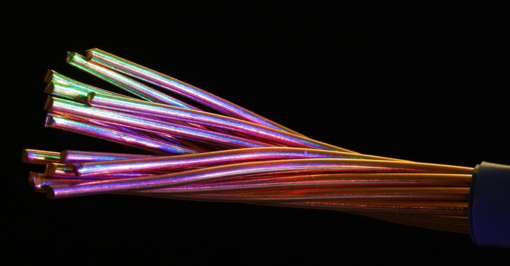 Vibrant multicolor fiber optic cables against a dark setting, showcasing technology and design.