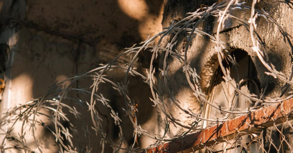 Close-up of barbed wire casting shadows on an old wall, creating dramatic effects.