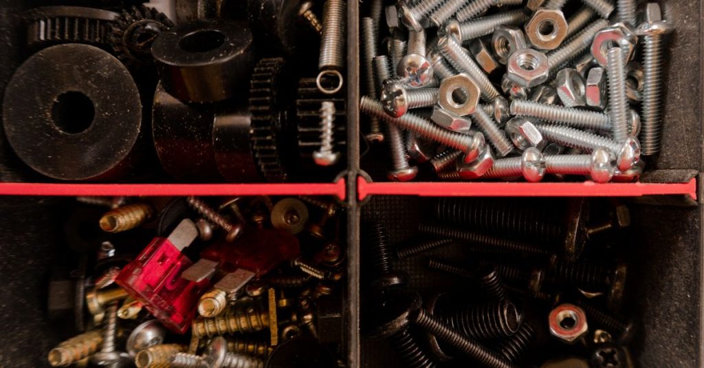 Close-up of various screws and bolts organized in a toolbox compartment.