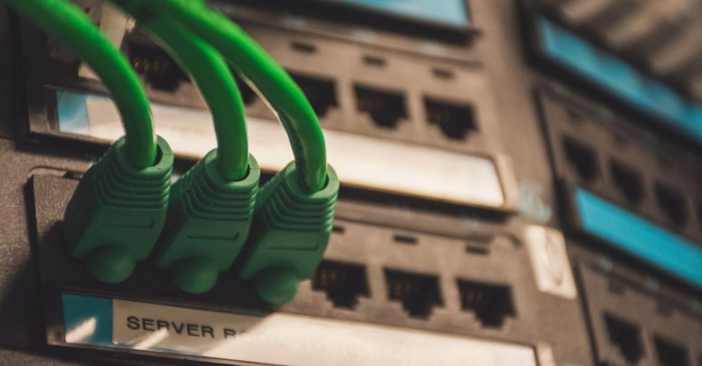 Close-up of green network cables plugged into server ports, showcasing technology setup.