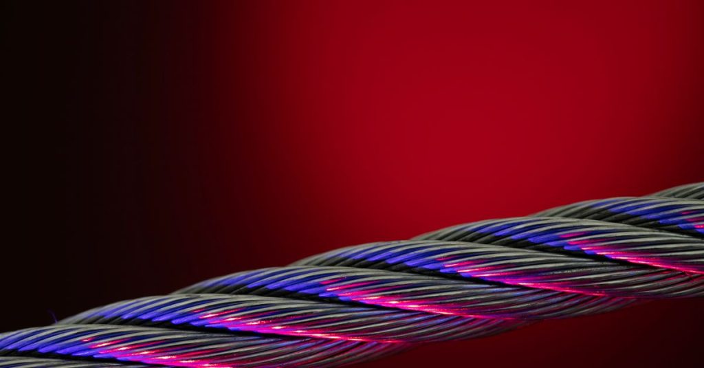 Close-up of a colorful twisted wire against a vivid red background.