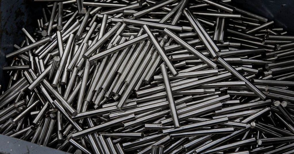 Close-up of numerous stainless steel rods in a container, showcasing industrial metal texture.