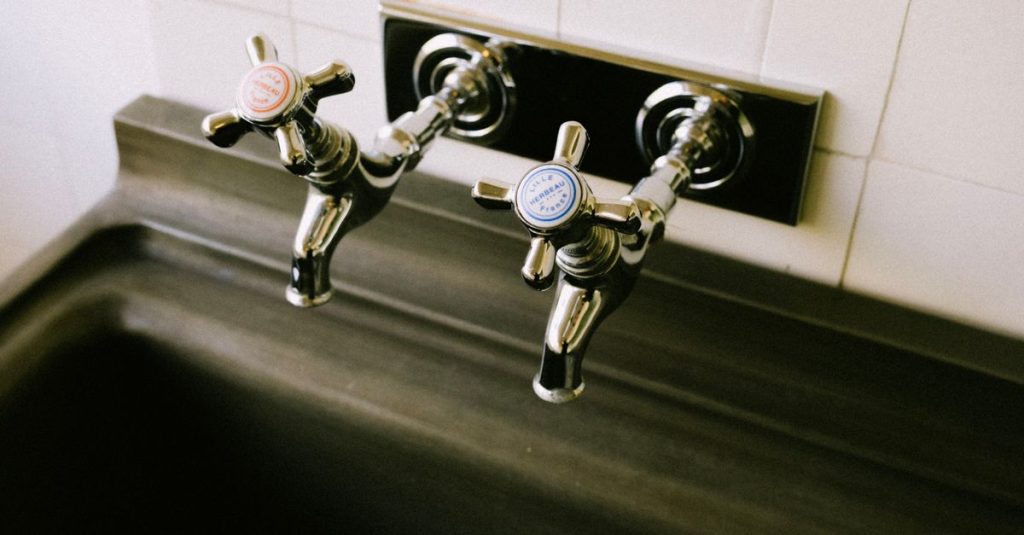 Detailed view of chrome sink faucets with classic hot and cold labels in a kitchen setting.