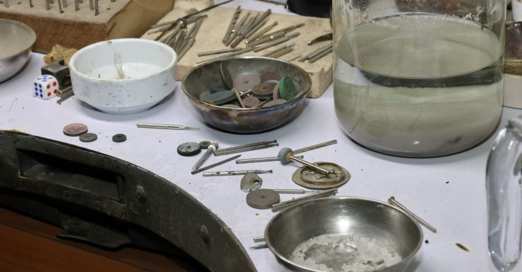 A detailed view of a jeweler's workbench with various tools and materials for crafting and repair.