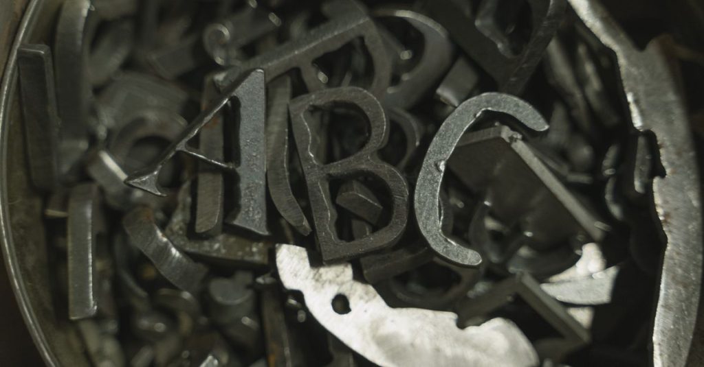Detailed view of assorted metal letter cutouts in a container, showcasing industrial craftsmanship.