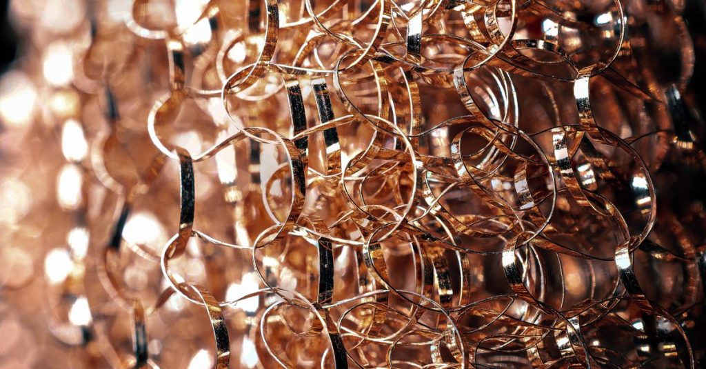 Entangled metal wire with rounded edges and glowing surface on blurred background in twilight