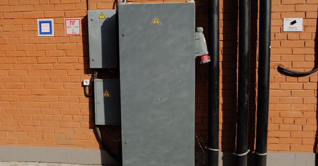 Outside cabinet of electrical power supply system installed along brick wall in sunny day