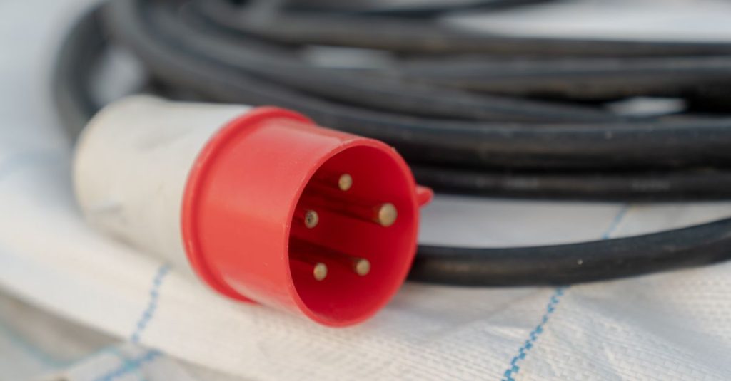 Detailed view of a red industrial electrical cable plug with visible pins.
