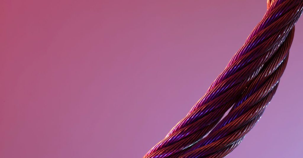 Detailed close-up of twisted metal wires against a gradient purple background, showcasing texture and color contrast.