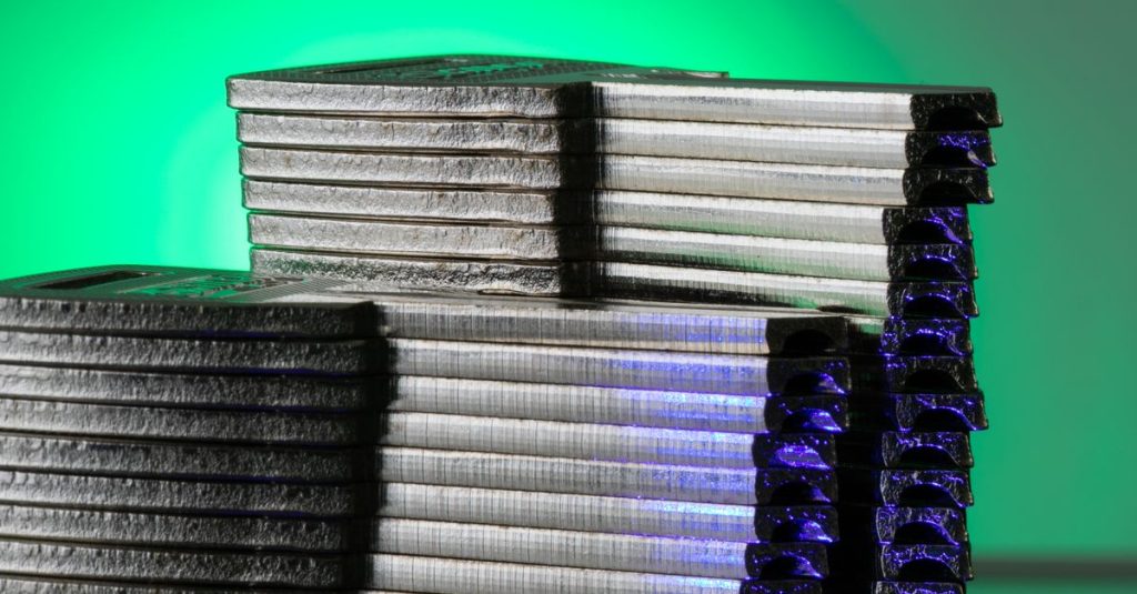 Close-up of stacked metallic discs reflecting green and blue light.