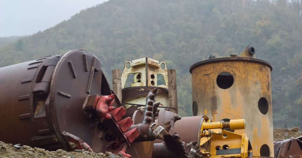 Abandoned industrial machinery rests on a misty hillside, creating a moody atmosphere.