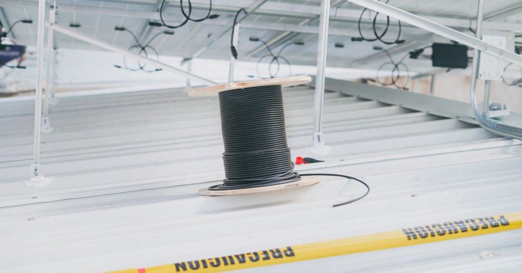 Coiled cable on a rooftop with solar panels, showcasing electrical installation for renewable energy.