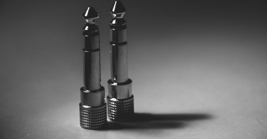 Black and white close-up of metallic audio jack connectors on a flat surface, showcasing modern technology.