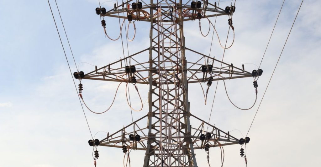Steel transmission tower with power lines extending across the sky, showcasing modern infrastructure.