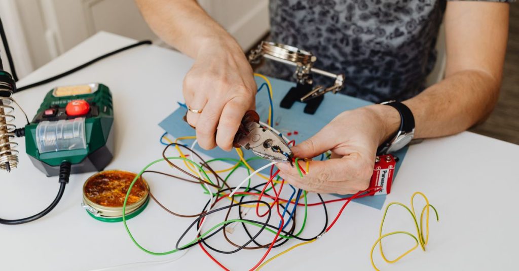 A technician precisely cuts and organizes colorful wires using pliers, showcasing expertise in wiring tasks.