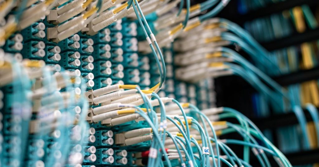 From below of long thin blue cables connected to row of small white connectors on system block in data center