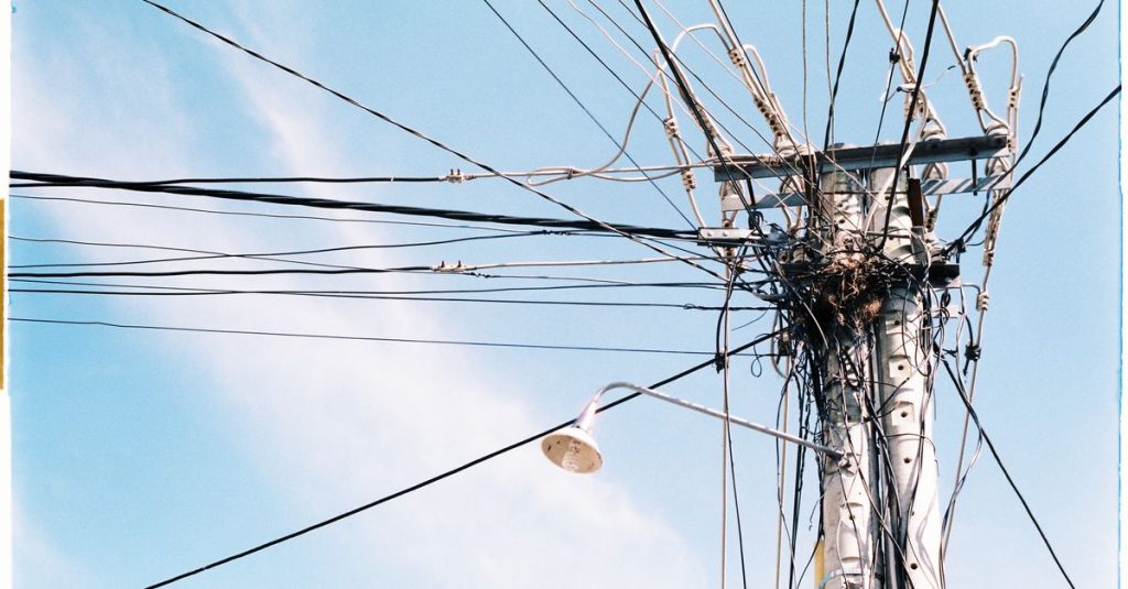 An intricate network of power lines and a lamp post against a clear blue sky.