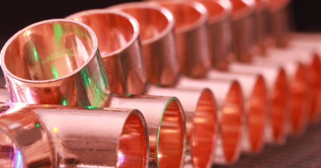 Copper plumbing fittings arranged in a row, showcasing metallic texture and industrial detail.