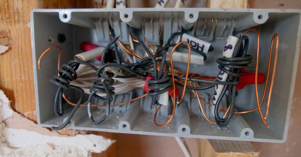 Detailed view of an open electrical switchboard with tangled wires and cables.