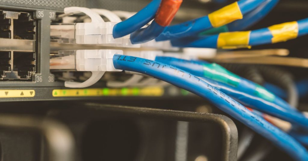 Network switch and blue ethernet cable with white tips connected to system for maintenance