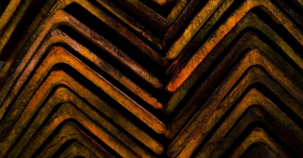 Close-up of rusty steel beams arranged in a geometric pattern, showcasing industrial texture.