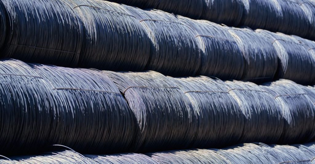 Close-up of stacked industrial steel wire coils glistening in sunlight.