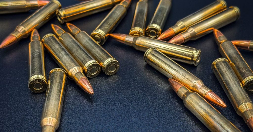 A detailed close-up of scattered rifle bullets on a dark surface, showcasing ammunition details.