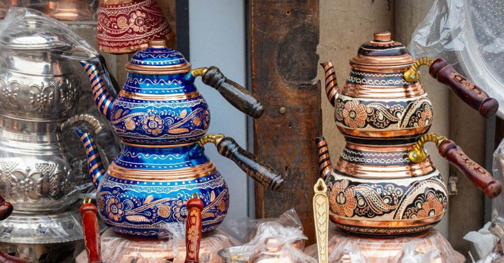Colorful and intricately designed metal teapots on display at a market stall, showcasing traditional craftsmanship.