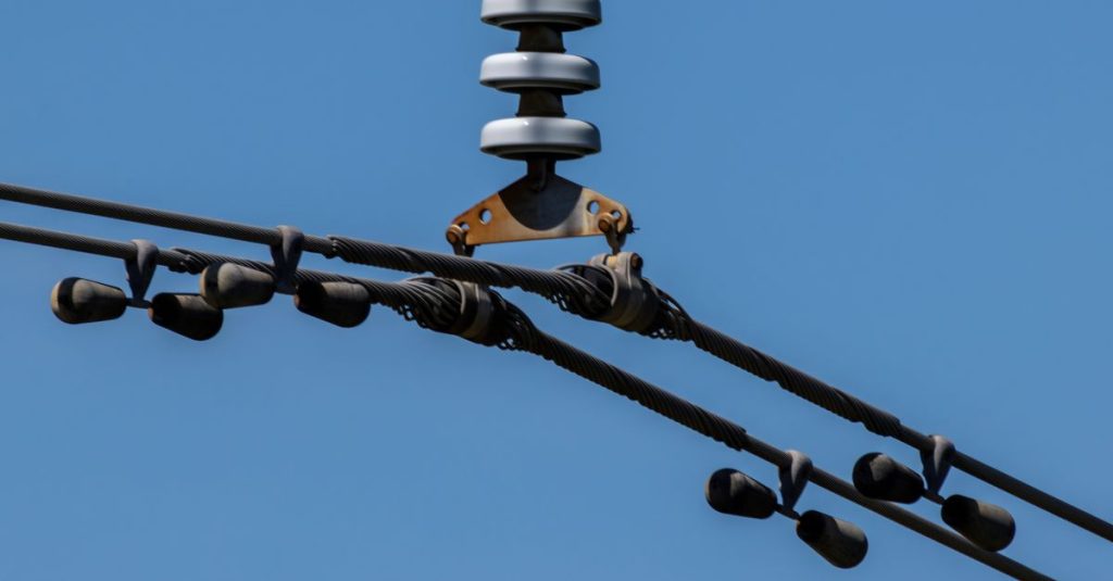 Detailed view of overhead power lines with blue sky background. Ideal for energy themes.