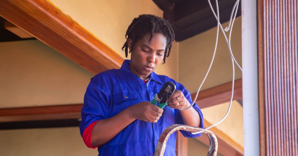 Professional electrician working on wiring in an indoor setting, demonstrating skill and concentration.