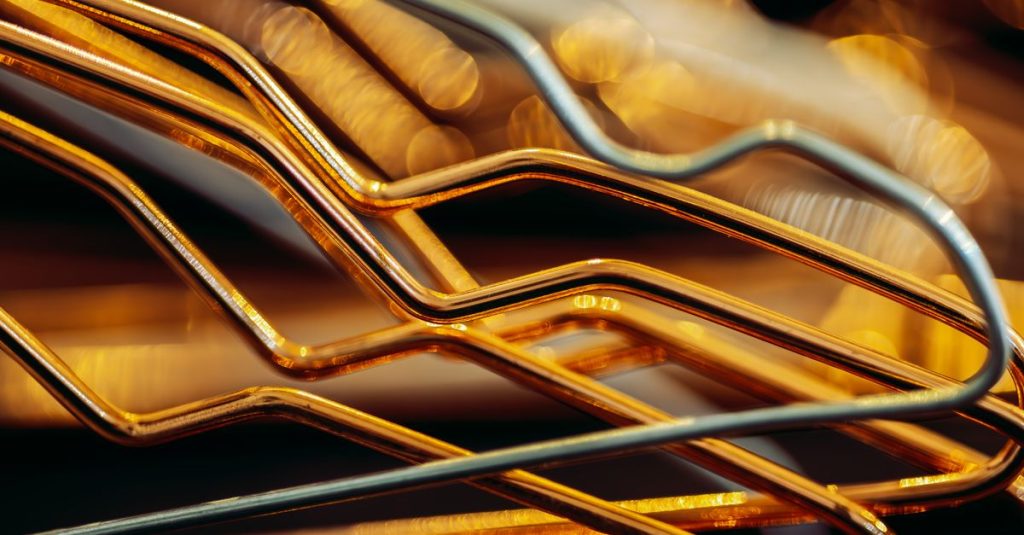 Close-up of golden metallic abstract shapes creating a geometric pattern with bokeh effect in the background.
