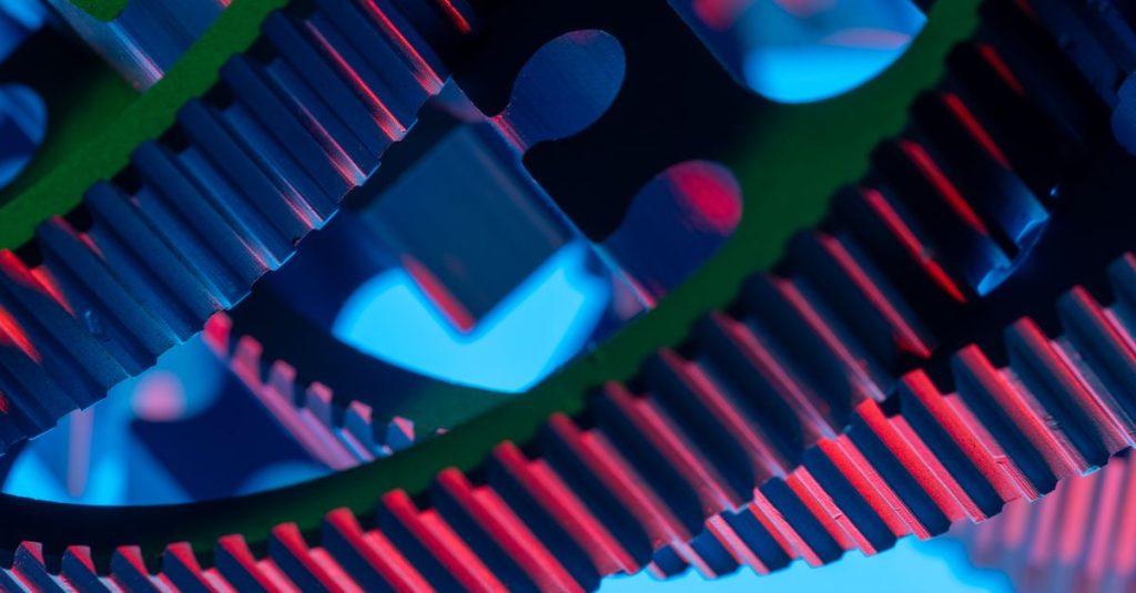Vibrant close-up of interlocking gears illuminated with colorful lights, showcasing industrial precision.
