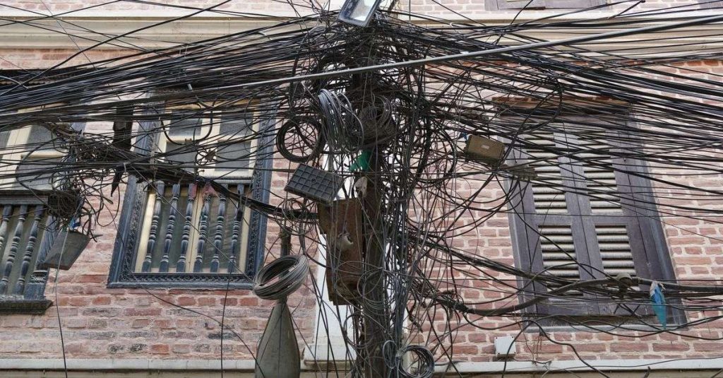 A chaotic array of electrical wires in front of a brick building in Kathmandu, Nepal.